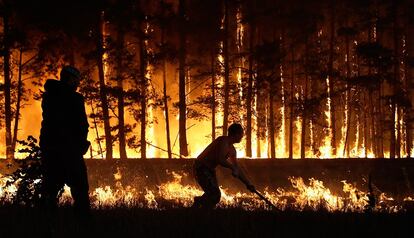 Unos retenes tratan de levantar una barrera para cortar el fuego en la localidad de Dolginino, Rusia.