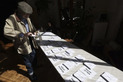 Un hombre elige una papeleta electoral en un centro de votaciones en París.