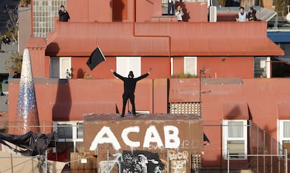 Un activista permanece en la azotea de uno de los edificios okupados mientras algunos vecinos contemplan el desalojo.