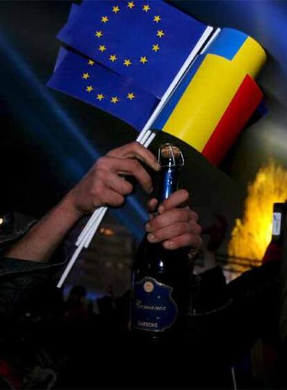 Un ciudadano rumano con las banderas de la Unión Europea y de su propio país descorcha una botella de champán para celebrar el ingreso de Rumanía.