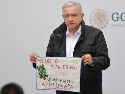 El presidente de México, Andrés Manuel López Obrador, posa con un bordado hecho por los familiares de los 43 estudiantes desaparecidos de Ayotzinapa, en Ciudad de México, en septiembre de 2020.