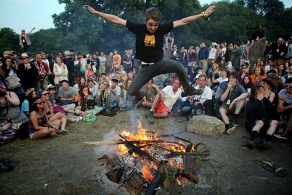 Un hombre salta por encima de una hoguera en una de las zonas de descanso del festival de Glastonbury, 26 de junio de 2013.