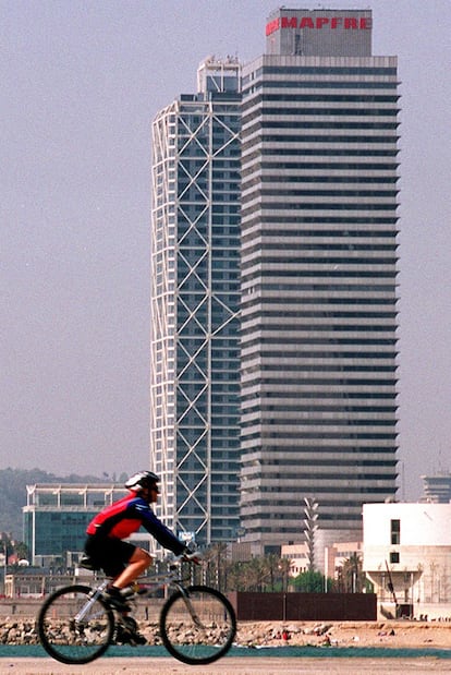 Un ciclista pasea ante la torre Mapfre en Barcelona.