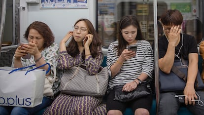 Varias personas usan su móvil en el metro de Seúl.