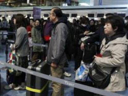 Pasajeros esperan en un fila para comprar los billetes en el aeropuerto de Tokio