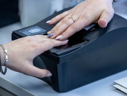 Una mujer captura sus huellas dactilares en un escáner.