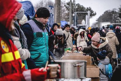 Voluntarios sirven comida caliente a los refugiados que huyen de la guerra en la frontera rumano-ucrania, en Siret. Entre tenderetes de ayuda, mantas tiradas por el suelo y coches aparcados en los arcenes, también forman parte del agitado paisaje de Siret los rumanos que han venido a ayudar.