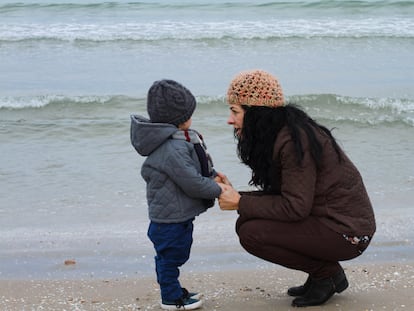 Mother talking to her son in front of the sea in winter.