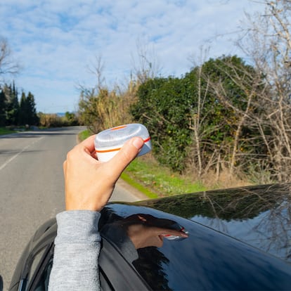 El brazo de una persona colocando la baliza en el techo de su coche.