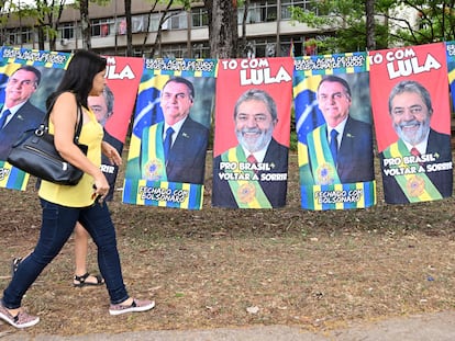 Una mujer pasa frente a unas mantas con los rostros de los candidatos, en Brasilia.