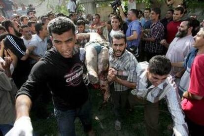 Tres palestinos transportan el cadáver de uno de los ocupantes del automóvil alcanzado por un misil israelí.