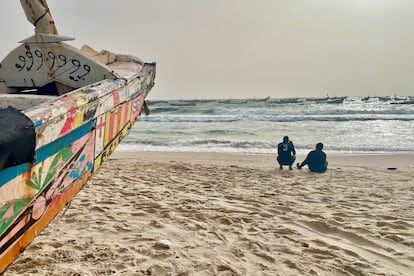 Dos hombres cerca de una piragua, un barco de madera utilizado tradicionalmente para la pesca en Mauritania y África Occidental, en una playa de Nuakchot, Mauritania, en junio de 2022.