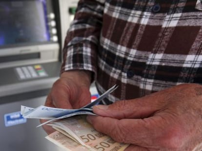 Un hombre saca dinero de un cajero autom&aacute;tico.