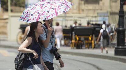 Dos turistas pasean por el centro de Sevilla.