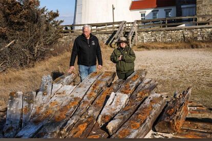Tony Femminella, executive director of the Fire Island Lighthouse Preservation Society, and Betsy DeMaria, museum technician with Fire Island National Seashore, stand beside a section of the hull of a ship believed to be the SS Savannah, at the Fire Island lighthouse, Friday, Jan. 27, 2023, in New York.