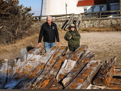 Tony Femminella, executive director of the Fire Island Lighthouse Preservation Society, and Betsy DeMaria, museum technician with Fire Island National Seashore, stand beside a section of the hull of a ship believed to be the SS Savannah, at the Fire Island lighthouse, Friday, Jan. 27, 2023, in New York.