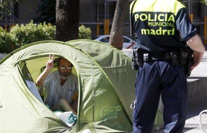 Marian Stanciu, trabajador de seguridad privada y presidente de la SELA-CE (Asociación española que defiende los derechos y libertades del personal de seguridad privada), en su tienda de campaña frente a un agente de la policía local de la capital madrileña.