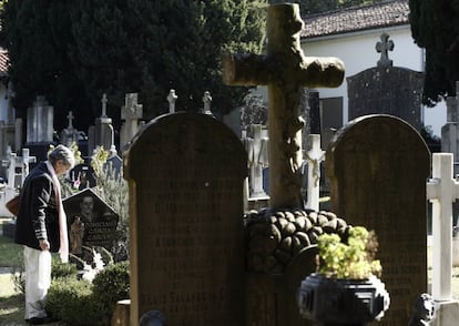 Una persona coloca un ramo de flores en una tumba del cementerio de Pamplona.