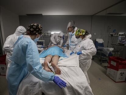 Varios sanitarios trabajan con un paciente infectado por coronavirus en estado muy grave, en una de las salas de UCI del Hospital Isabel Zendal de Madrid.