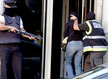 Un agente de la Policía Nacional conduce a uno de los detenidos hoy en un polígono industrial de Usurbil (Guipúzcoa), hasta la comisaría de San Sebastián, dentro de la operación coordinada por el juez Garzón en la que han sido detenidas tres personas.