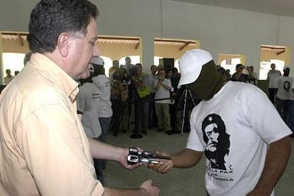 Luis Carlos Restrepo (izquierda) recibe las armas de un guerrillero de las FARC, el 16 de noviembre en Ibagué.