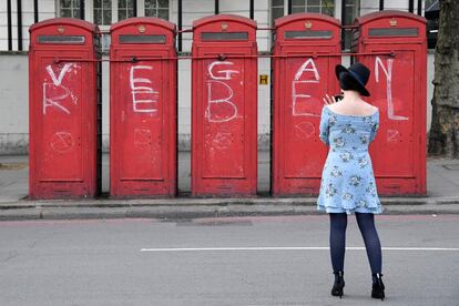 Una semana después del inicio de las protestas, Scotland Yard confirmó al menos 1.065 detenidos. En la foto, una mujer fotografía un eslogan político en cabinas telefónicas durante la protesta de Extinction Rebellion (XR) en Marble Arch en Londres, el 22 abril 2019