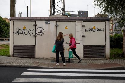 Dos mujeres pasan frente a un transformador eléctrico del barrio de Padre Pío en Sevilla. 