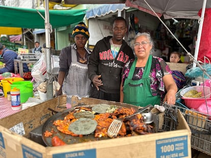 Edith Ossias and her husband pose for a picture alongside Mrs. Chole in her streetside restaurant, in La Merced market in Mexico City.