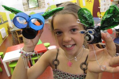 Una niña sostiene dos juguetes hechos con materiales reciclados en el Natur Txoko de Urgull.