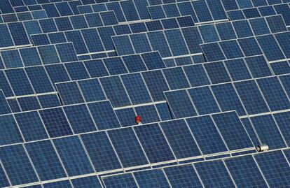 Un empleado camina entre paneles solares en una planta de energía solar, en las afueras de Dunhuang (China).