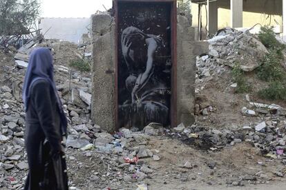 Una mujer observa el 'banksy' en su colocación original en la puerta de un edificio de Gaza, el 28 de febrero de 2015.