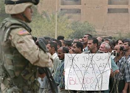 Ex soldados iraquíes con un cartel que dice: "Mejor pagar al Ejército iraquí que pagar con sangre del Ejército de EE UU".