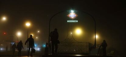 Varias personas entran en el metro a primera hora de una mañana de densa niebla.