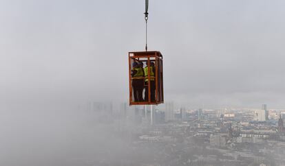 Periodistas colgados de una jaula observan las obras de contrucción de la torre Henniger, en Fráncfort.