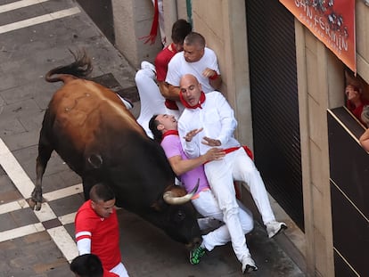 Dos mozos, acorralados por un toro en la curva de Mercaderes al inicio de Estafeta, durante el cuarto encierro de los sanfermines.