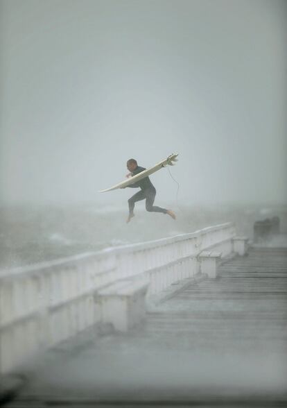 Un surfista salta desde muelle en Port Phillip Bay para coger las olas durante la tormenta que azota la zona de Melbourne.