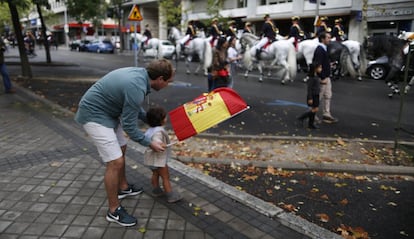 Un hombre con un niño se prepara para ver el desfile militar del 12 de Octubre este viernes en Madrid.
