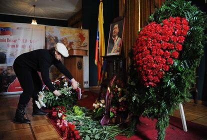 Una mujer deposita flores frente a un retrato de Hugo Ch&aacute;vez en la embajada de Venezuela en Mosc&uacute;.