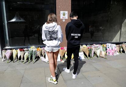 Dos jóvenes con sudaderas de Ariana Grande dejan flores en la plaza de Santa Ana en Manchester, en el primer aniversario del atentado en el Manchester Arena. 