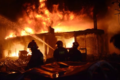 As equipes de resgate temem que aumente o número de mortos, segundo declarou Ali Ahmed, o chefe do serviço nacional de bombeiros. Na imagem, bombeiros e vizinhos ajudam a apagar o fogo em um dos edifícios.