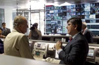 El rey escucha las explicaciones del director técnico y de operaciones de Hispasat, Antonio Abad, durante la visita que ha realizado hoy al centro de control de satélites de la compañía, en Arganda del Rey.