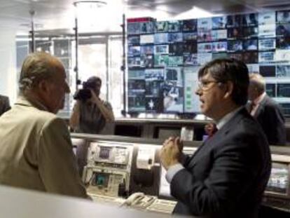 El rey escucha las explicaciones del director técnico y de operaciones de Hispasat, Antonio Abad, durante la visita que ha realizado hoy al centro de control de satélites de la compañía, en Arganda del Rey.