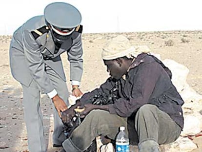 Un gendarmes ayuda a Soldi, inmigrante de Gambia, a levantarse.