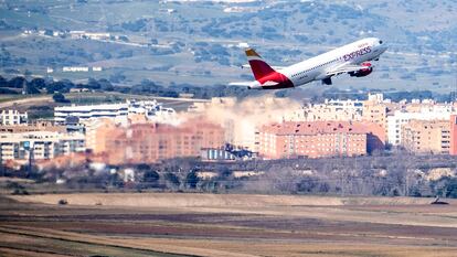Vista panorámica del aeropuerto Adolfo Suárez de Madrid y un avión de Iberia Express despegando.