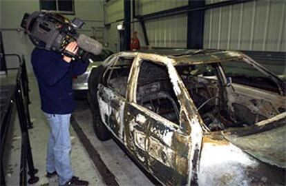 Un cámara recoge imágenes del coche calcinado usado por los terroristas para asesinar al empleado de Correos.