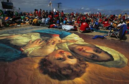 Un numeroso grupo de fieles acampa junto a una imagen gigante de la Virgen Mar&iacute;a y Jesus. en la playa.