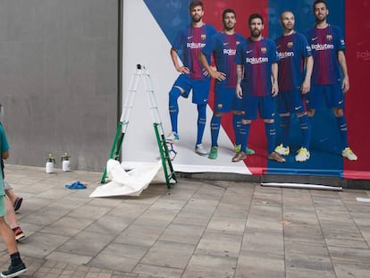 Un chico con la camiseta de Neymar pasa frente al nuevo póster sin el brasileño.