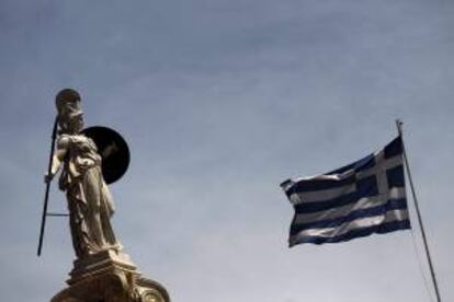 Una bandera griega ondeando al lado de la estatua de la diosa Palas Atenea en el centro de Atenas. EFE/Archivo