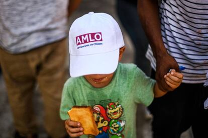 Un niño de la caravana migrante lleva una gorra de la campaña de López Obrador.
