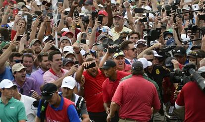 Tiger Woods y Rory McIlroy (abajo a la izquierda de la imagen), rodeados de fans en su camino hacia el 'green' número 18, durante la ronda final del Tour Championship en Atlanta (EE UU), el 23 de septiembre de 2018.